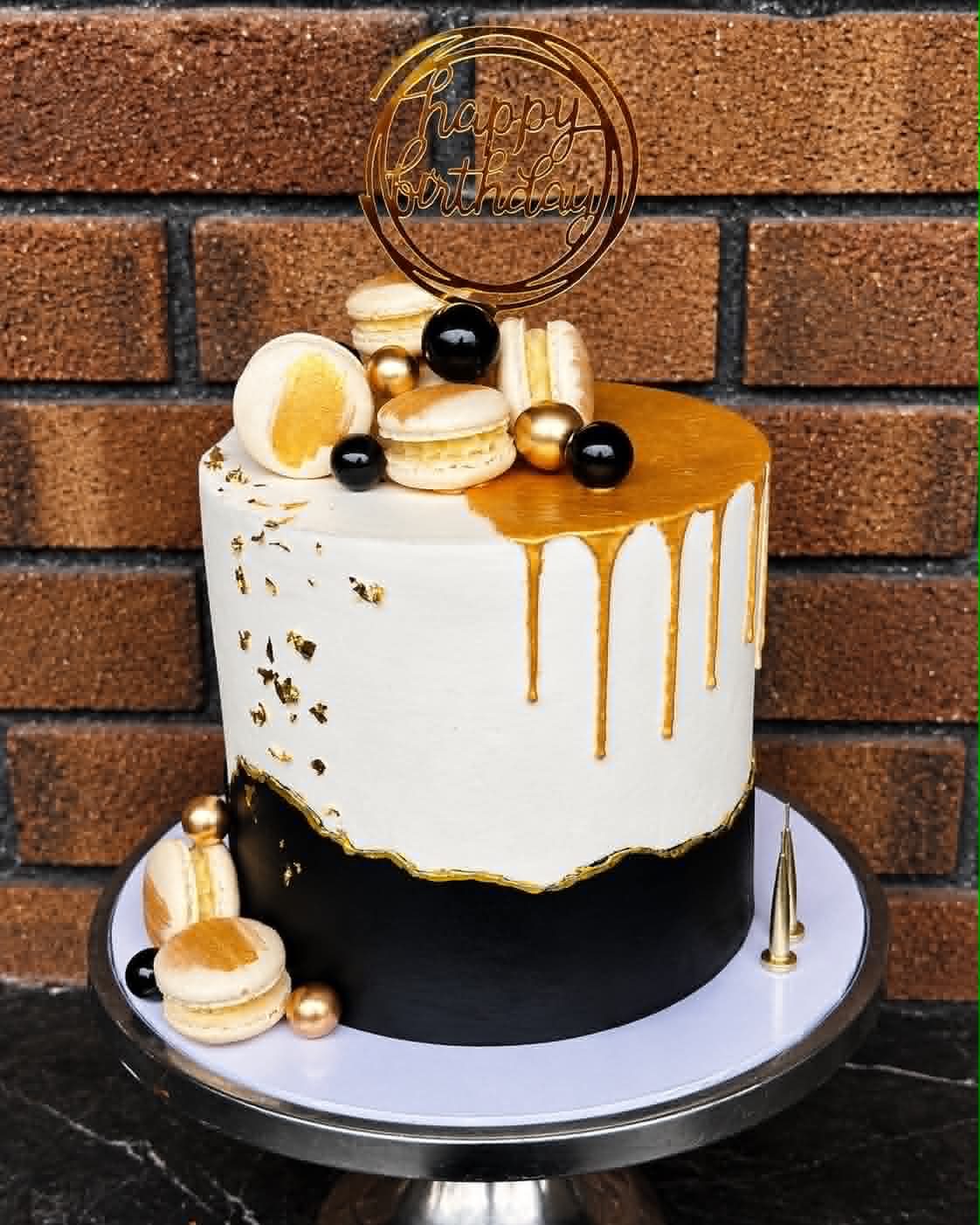 Black and white birthday cake with gold drip, gold leaf, macarons and black pearl decorations